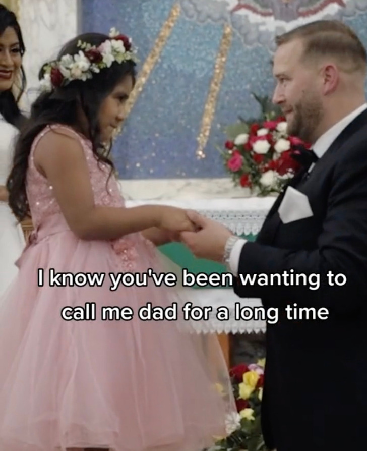 A man in a black suit takes the hand of a young girl at a church altar.